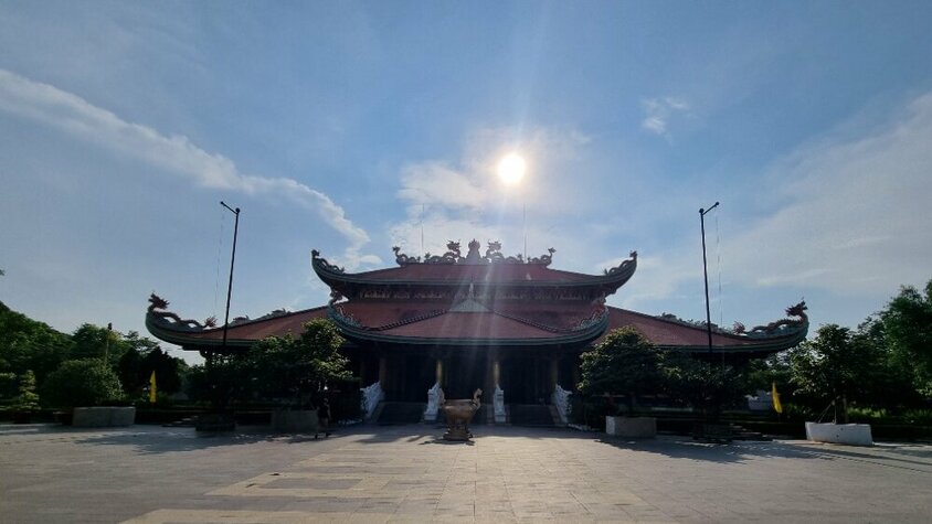 Ein traditioneller vietnamesischer Tempel mit geschwungenem Dach im Sonnenlicht, umgeben von Bäumen – Momentaufnahme aus Jan Wengryns Entdeckungsreise durch Südostasien.