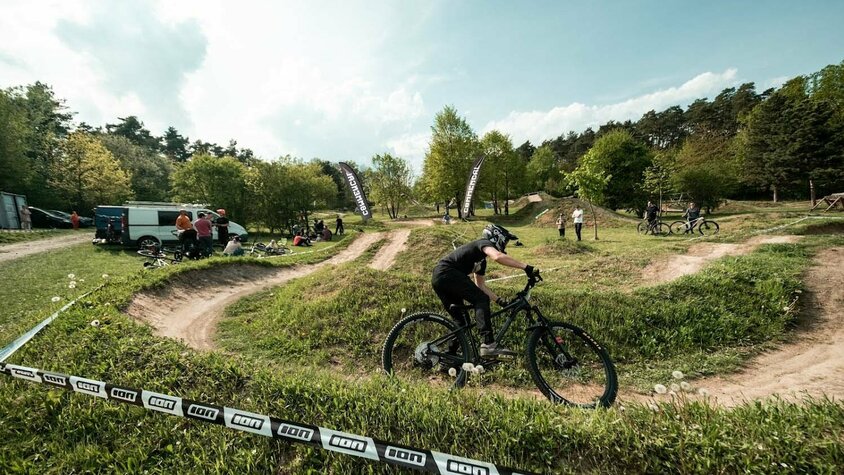 Radek Šimek in Action – Leidenschaft fürs Mountainbiken Radek Šimek fährt mit Helm und Mountainbike über eine kurvige Dirt-Strecke beim Training.