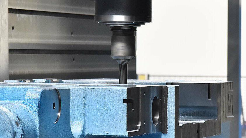 Präziser Fräsvorgang in der mechanischen Bearbeitung Nahaufnahme eines Fräsvorgangs in der mechanischen Bearbeitung. Ein CNC-Fräswerkzeug bearbeitet präzise ein blaues Metallwerkstück. Die Drehbewegung des Fräskopfes und die Einspannung des Werkstücks deuten auf einen hochpräzisen Bearbeitungsprozess hin. Der Hintergrund zeigt die kontrollierte Umgebung innerhalb der CNC-Maschine, die für die Fertigung komplexer Metallteile optimiert ist.