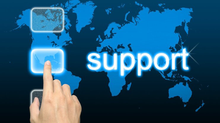 Hand pointing at world map with "Support" text – symbolic image for international customer service