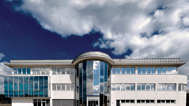 Exterior view of the administration wing at weba’s development headquarters in Dietach under a blue sky with clouds.