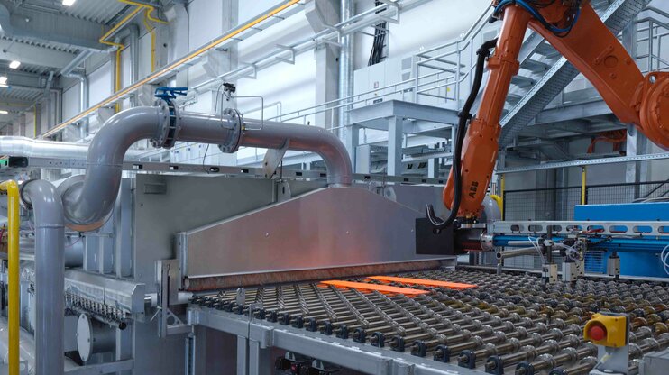 Automated hot forming system with robotic handling and a glowing steel sheet for the production of high-strength lightweight components.