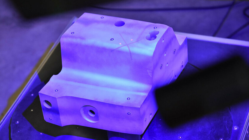 Digitalisierung - Qualitätssicherung im Werkzeugbau Ein Stahleinsatz befindet sich zentriert auf einer Drehscheibe in einem technischen Labor. Ein 3D-Scanner, der über der Drehscheibe positioniert ist, digitalisiert und analysiert das Objekt sorgfältig. Dies verdeutlicht die Digitalisieungs-Initiative von weba in der Qualitätssicherung.