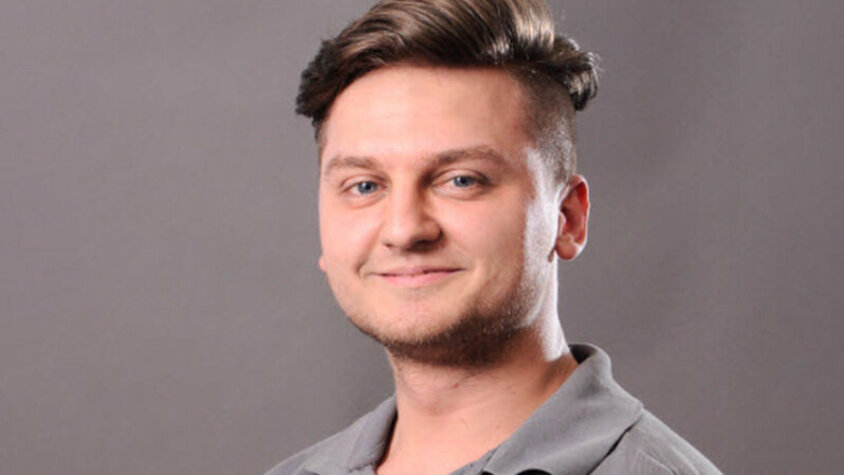 Michal Skácel – Erfolgreich mit weba Porträt eines jungen Mannes mit kurzem, seitlich rasiertem Haar und einem freundlichen Lächeln. Er trägt ein graues Polohemd und blickt direkt in die Kamera. Der Hintergrund ist neutral und grau.
